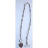 A silver necklace having an oval link chain with a toggle clasp and heart pendant. Measures 19