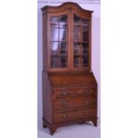 An Edwardian solid oak bureau bookcase raised on s