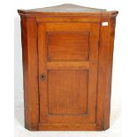 A 19th Century George III golden oak hanging corner cabinet having a panelled design door with a