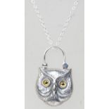 A silver pendant necklace having a shield shaped lock pendant in the form of an owl with glass