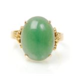 A stamped 14ct gold ring set with a round domed green jade cabochon with decorative floral design