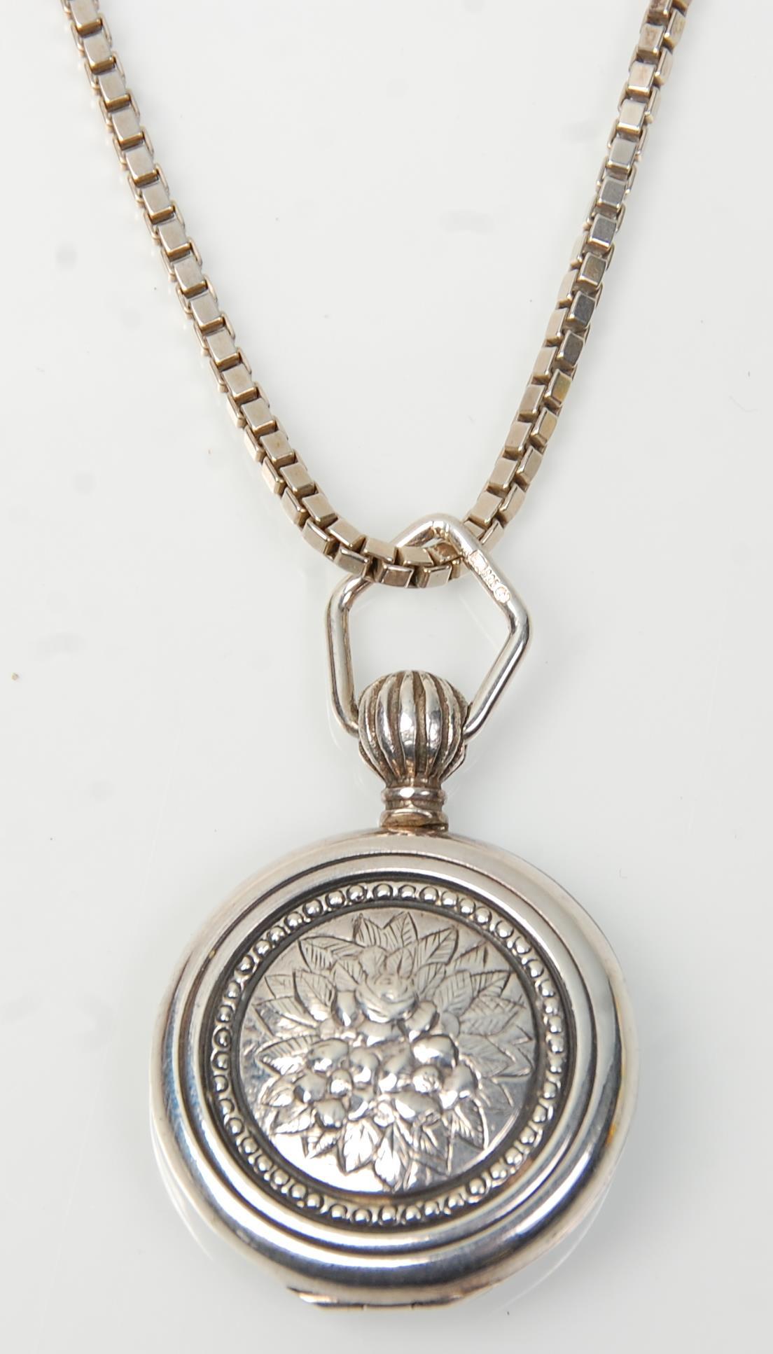 A stamped 925 silver locket of round form having repousse floral decoration on a stamped 925