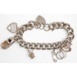 A thick link silver chain charm bracelet adorned with charms to include three textuard rings, crown,