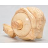 An unusual carved bone tape measure in the form of a mermaid with a carved rat set to the end of the