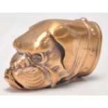 A brass vesta case in the form of a dogs head being set with orange glass eyes, having a match