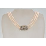 A vintage pearl necklace having three rows of graduating cultured pearls with a silver paste set box