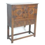 An early 20th Century 1920's carved Ipswich oak cupboard on stand having a twin door cupboard with