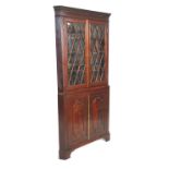 A 19th Century mahogany corner cabinet having a twin door cupboard base with carved panelled