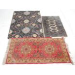 A mixed group of three rugs to include 100% wool black ground example with floral patterns, a