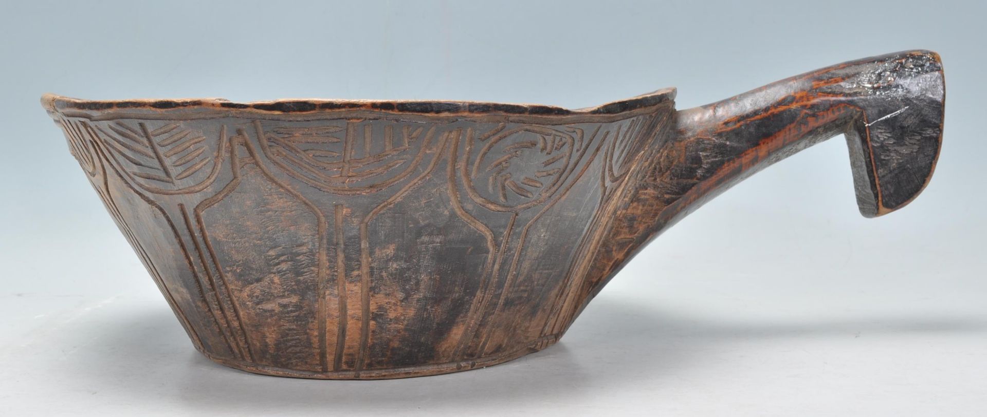A antique African carved hardwood tribal bowl of conical form having a large carved handle to one