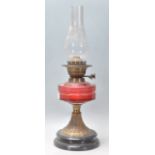A 19th Century Victorian oil lamp having a round black lacquered plinth base with a cranberry