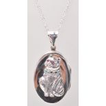 A stamped 925 silver pendant necklace having an oval locket with a raised cat wearing a collar set