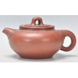 An early 20th Century Chinese Yixing red clay teapot of squat form having a short spout and finial