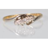A stamped 18ct gold crossover ring set with three diamond chips set in platinum. Weight 1.7g. Size