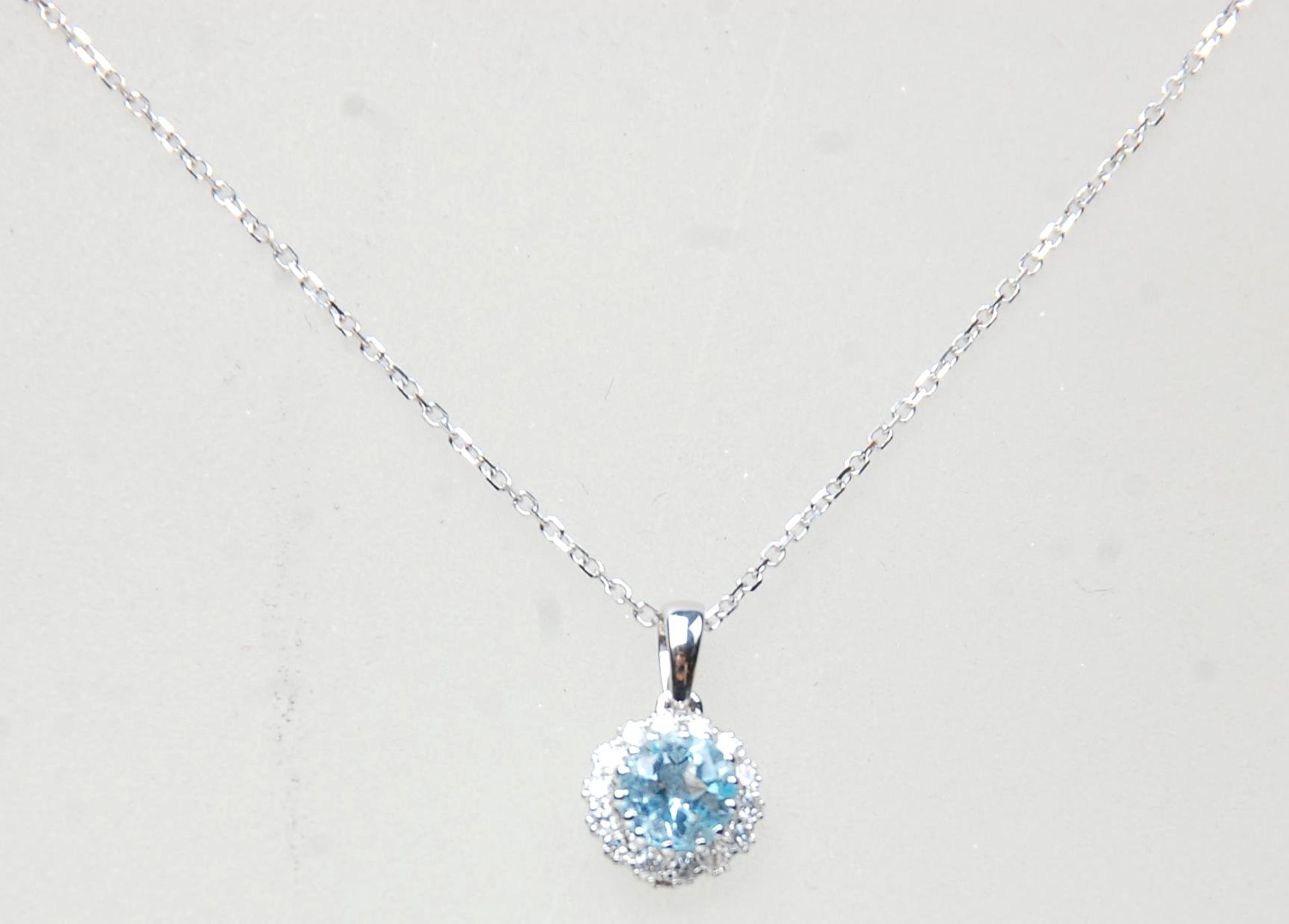 An 18ct white gold pendant necklace, the pendant set with a round cut topaz with a halo of diamonds.