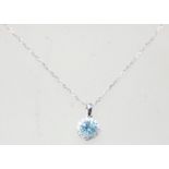 An 18ct white gold pendant necklace, the pendant set with a round cut topaz with a halo of diamonds.