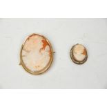 Two antique cameo brooches having oval carved conch shell panels, the larger mounted in yellow metal