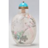 A 20th Century Chinese reverse painted scent bottle being decorated with birds and florals,