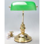 A vintage 20th Century bankers desk lamp having a round stepped base with a green glass rotating