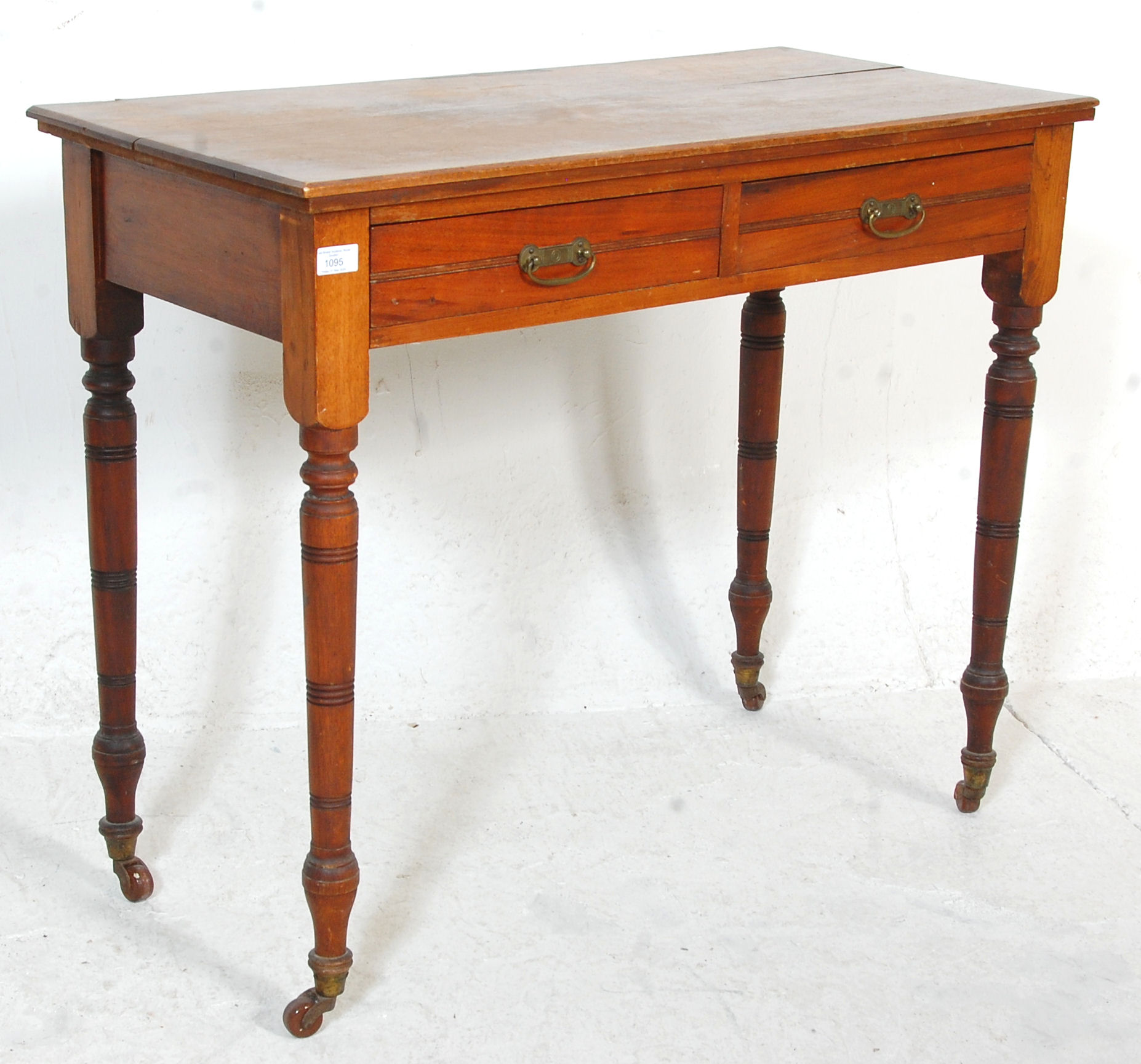 A late Victorian ash / oak writing table desk being raised on turned legs with castors having frieze