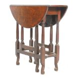 A 1920's solid oak gate leg folding leaf occasional side table raised on block and turned legs