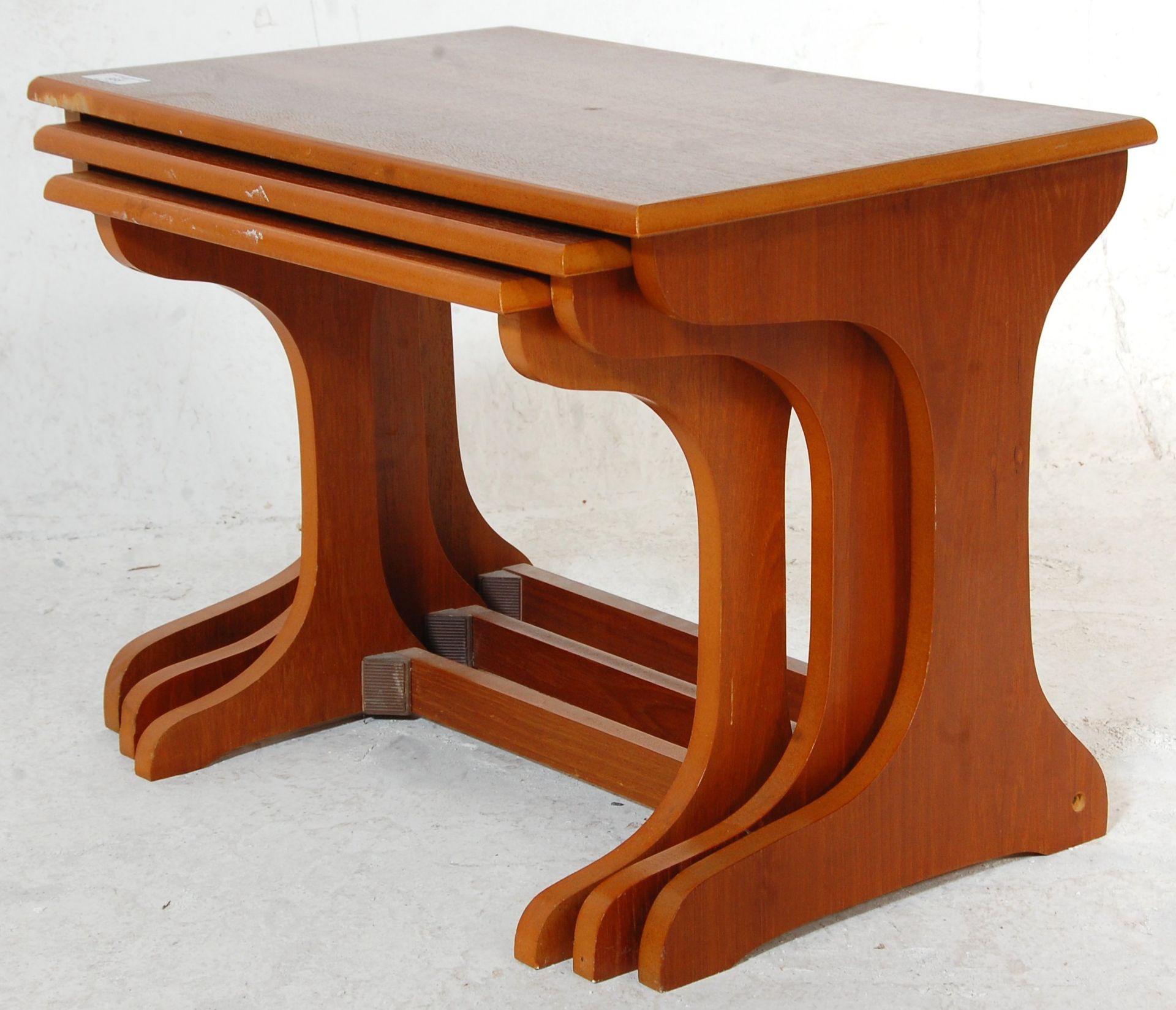 A 1970's vintage retro teak wood nest of tables having shaped legs united by stretchers with