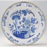 A large 18th Century Delft blue and white Chinese style wall charger plate being hand painted with