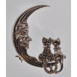 A stamped sterling silver brooch in the form of a crescent moon with two sitting cats set with