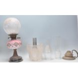 A 19th Century Victorian oil lamp having a pink curtain and tassel design reservoir with a bulbous