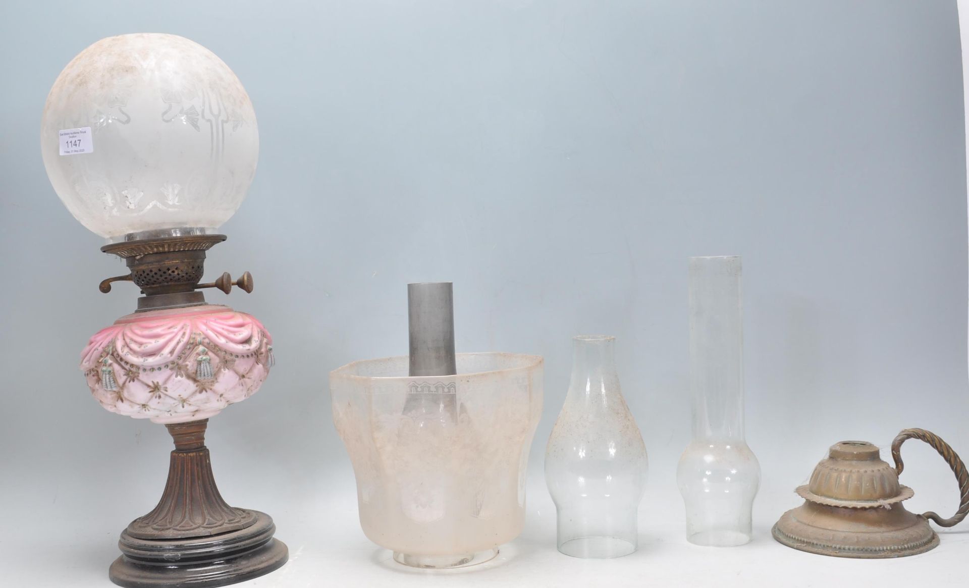 A 19th Century Victorian oil lamp having a pink curtain and tassel design reservoir with a bulbous