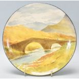 A late 19th Century Doulton Lambeth Faience plate having a hand painted landscape scene depicting