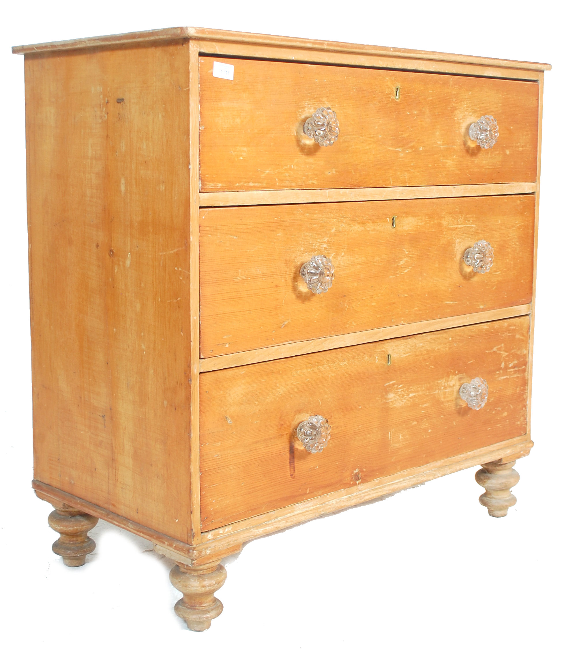 A Victorian pine cottage small chest of drawers being raised on bun feet with glass handles to the 3