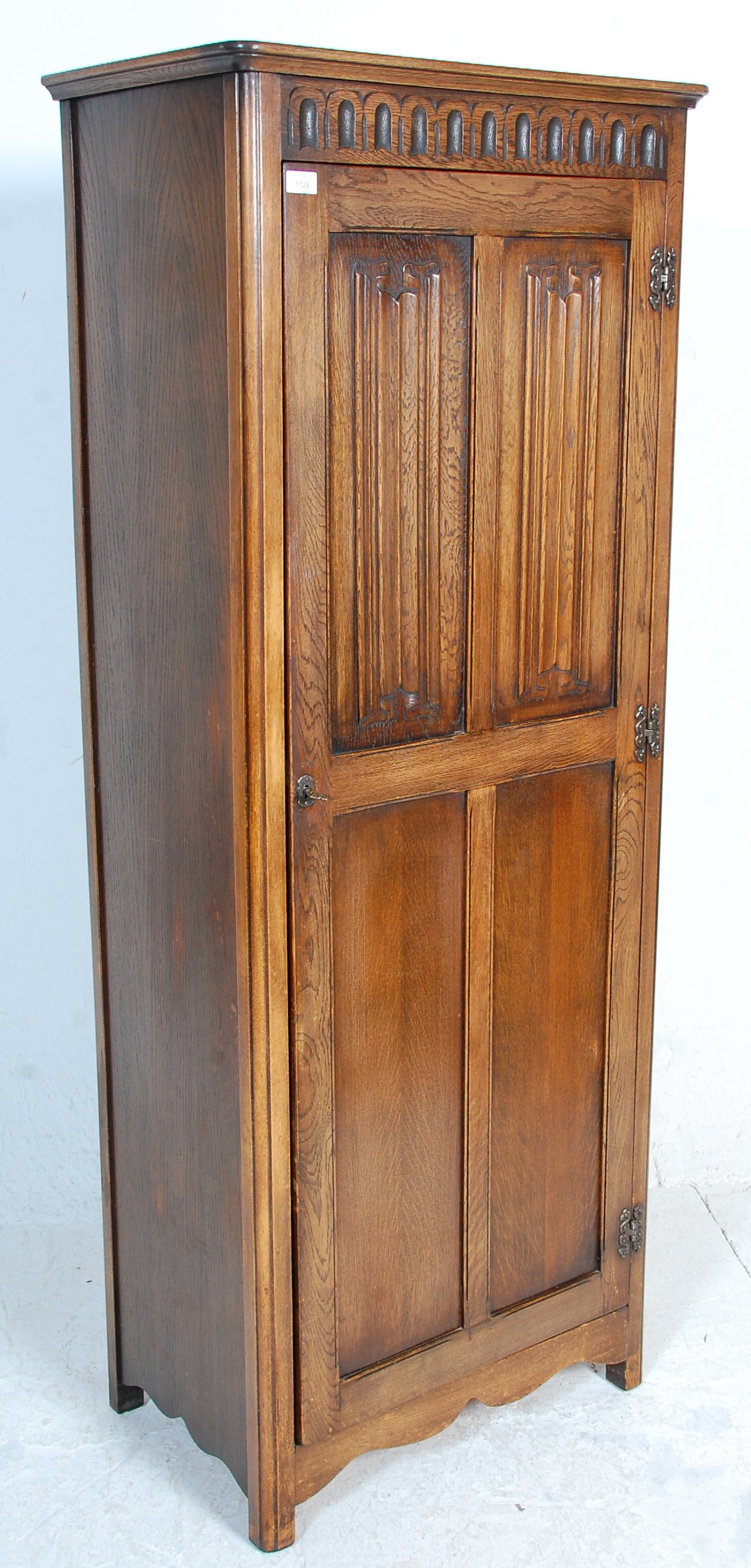 A 1930's oak Art Deco wardrobe having a singe four panelled door with carved graphic decoration to