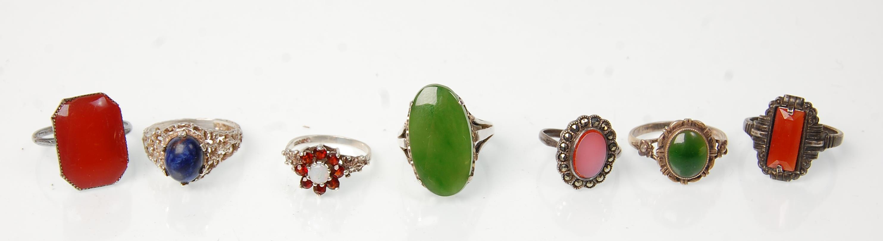 A group of seven silver rings to include a green stone panel ring (possibly jade) a lapis lazuli set