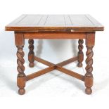 An early 20th Century oak draw leaf dining table having a square top on four barley twist supports