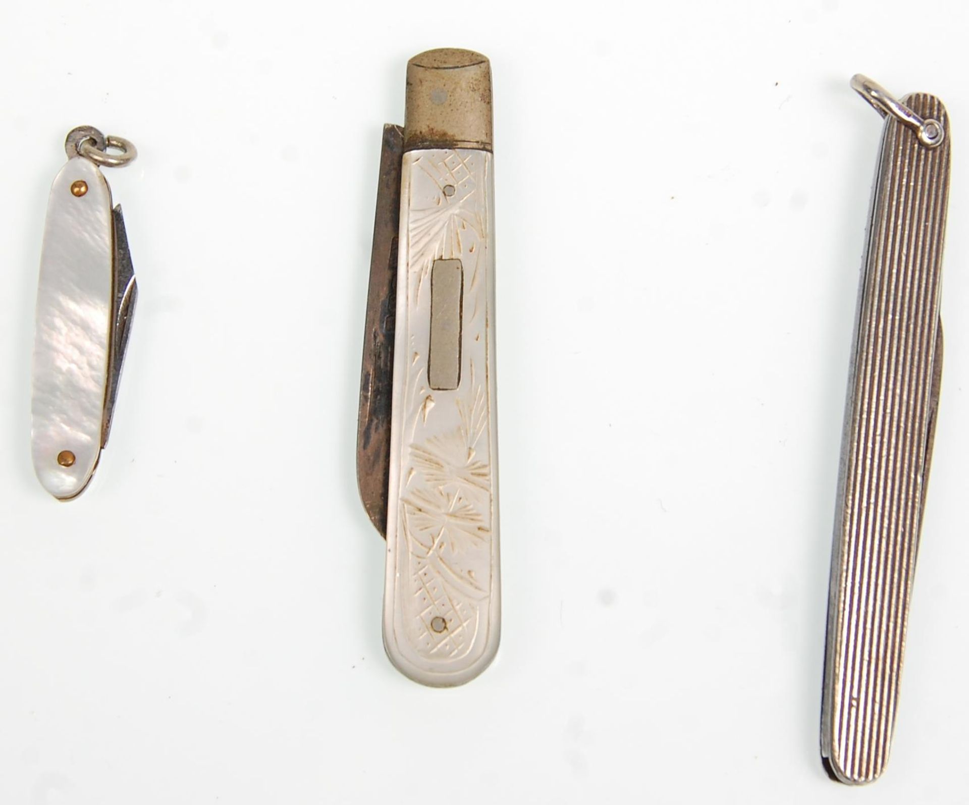 A group of three silver fruit knives to include a hallmarked folding knife with a mother of pearl