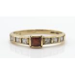 A 9ct gold ruby and diamond ring. The ring with cushion cut ruby flanked by inset diamonds to the