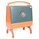 A vintage retro teak wood magazine rack, the fall front upholstered in blue leather with a crest