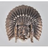 A stamped sterling silver brooch in the form of a Native American wearing a feather headdress,