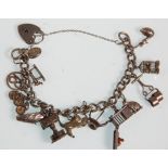 A silver charm bracelet adorned with many silver charms to include a cat playing with a ball, oil