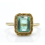 A 9ct gold and emerald ring. The ring set with a facet cut emerald in mount with rope twist border
