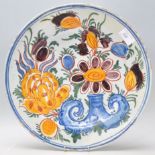 An 18th Century Delft polychrome wall charger plate having hand painted stylised floral decoration