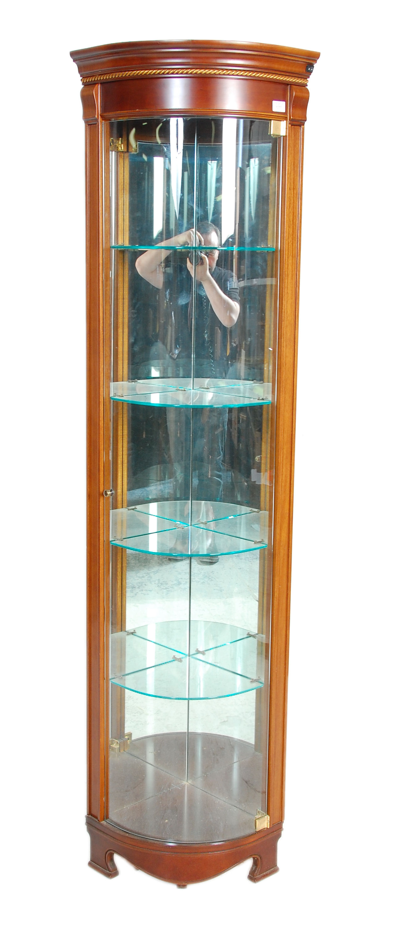 A 20th Century vintage shop display corner cabinet having a glazed bow front with glass shelves