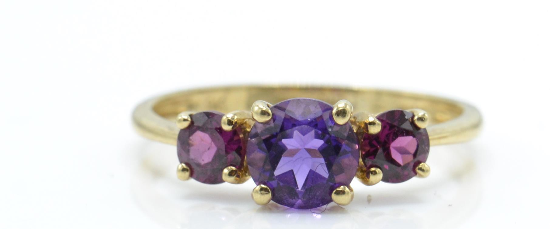 A 9ct gold Birmingham hallmarked 3 stone amethyst ring. The 3 round mixed cut amethysts in 4 prong