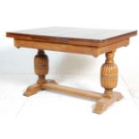 An early 20th Century oak draw leaf dining table having a rectangular top on bulbous cup and cover