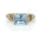 A 9ct gold  / 375 marked diamond and blue topaz ring. The cushion cut topaz with diamond set