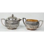 A matching silver plated creamer jug and lid sugar bowl having twin handles. Both repousse decorated