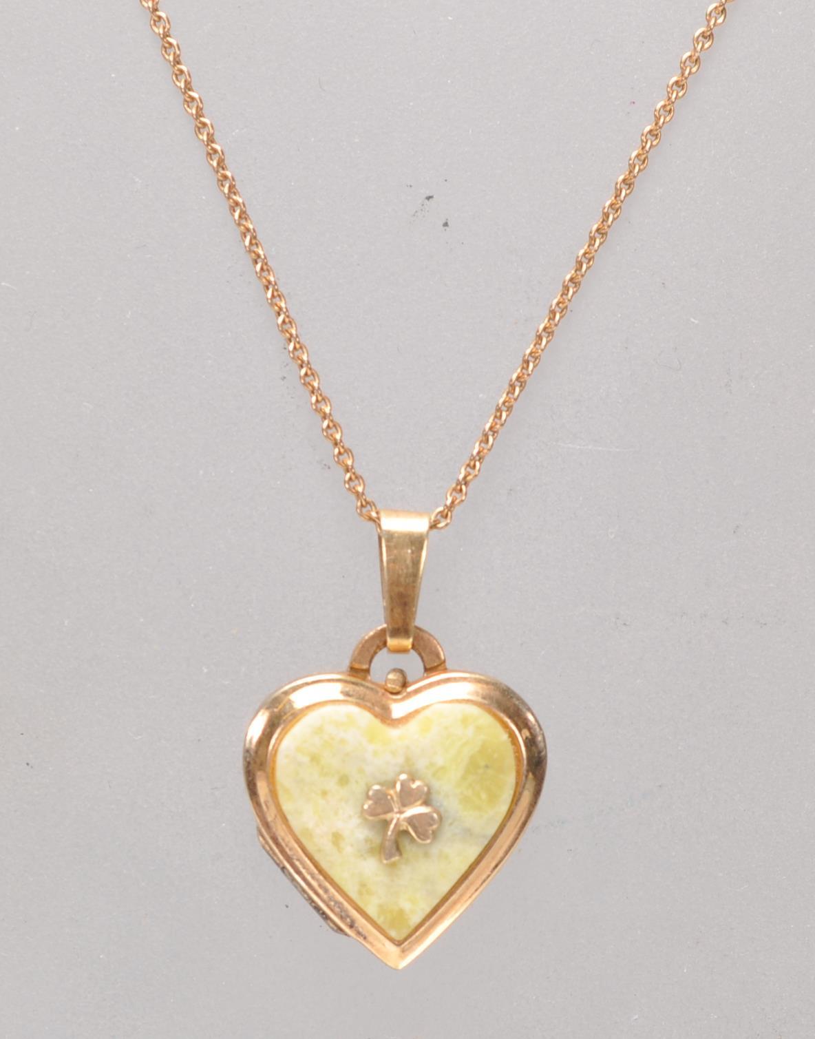 A stamped 14ct gold heart shaped pendant set with a green stone panel with a three leaf clover