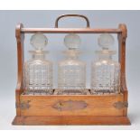 A 20th Century wooden drinks tantalus cabinet holding three cut glass decanters complete with