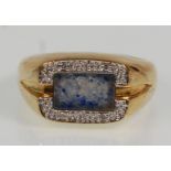A thick 9ct yellow gold ring set with a blue stone panel and split diamond illusion surround.